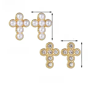 Detail of cross-shaped earrings featuring white pearls, clear crystals, and gold metal finish