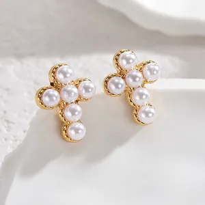 Macro shot of gold cross stud earrings featuring inlaid white round pearls with micro details