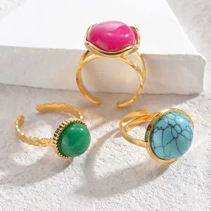 Vintage gold adjustable rings set with colorful gemstone cabochons on stone display