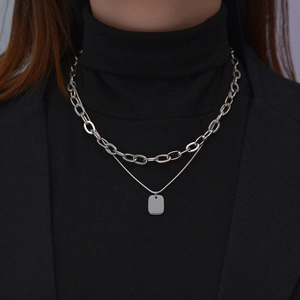 Silver layered stainless steel necklace with square pendant on black turtleneck clothing