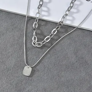 Detail of double-layered stainless steel necklace with square pendant on marble background
