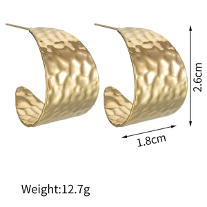 Detail view of gold hammer textured wide hoop earrings with size 2.6cm by 1.8cm