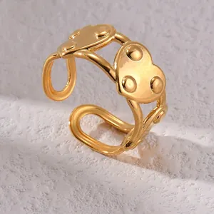 Bague ouverte cœur dorée minimaliste avec points en relief sur une surface en pierre