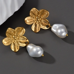 Vintage gold flower earrings with elegant baroque pearls on a textured grey background