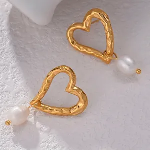 Vintage gold heart earrings with hammered texture and elegant white pearls on white stone