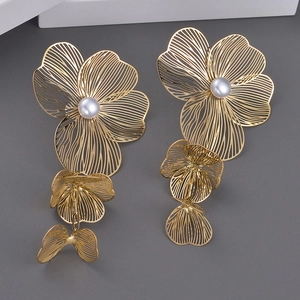 Exaggerated gold flower drop earrings with white pearls for a bold statement look