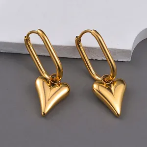French vintage style geometric gold heart drop earrings on a white textured stone background