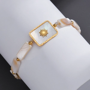 Detail of bohemian gold bracelet with rectangle shell inlay and sun relief design