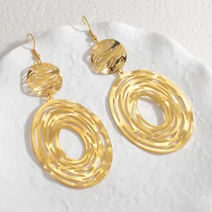 Detail of 18K gold-plated titanium steel geometric hollow earrings on white ceramic