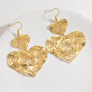 Detail view of 18K gold plated hollow heart drop earrings on a white display tray