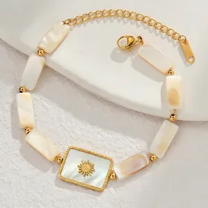 Elegant gold stainless steel bracelet with white shell inlays and a sun relief charm