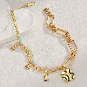 Elegant gold double-layered bracelet with heart pendants and green stone charms on stone base