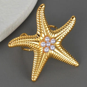 Exaggerated golden starfish open ring with pearl center on minimalist grey background