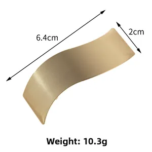 Détail de la pince à cheveux dorée ondulée avec dimensions 6.4cm x 2cm et texture mate