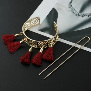 Detailed view of golden hollow floral hair pin and bracelet with red tassels on black background