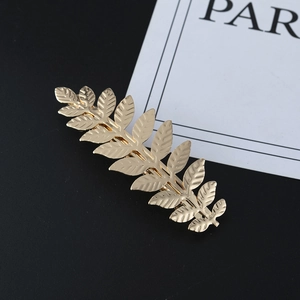 Elegant golden metal leaf hair clip with intricate vein patterns on black background