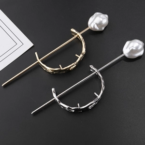 Detailed view of gold and silver D-shaped hairpins with baroque pearls on black texture