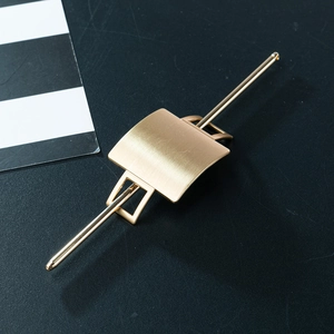 Minimalist matte gold hair fork with brushed metal texture on a dark background