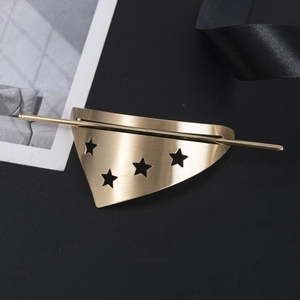 Macro shot of brushed gold triangular hair pin with hollow star patterns on black fabric