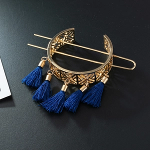 Detail of golden geometric hollow hair bun cuff with blue silk tassels on dark texture