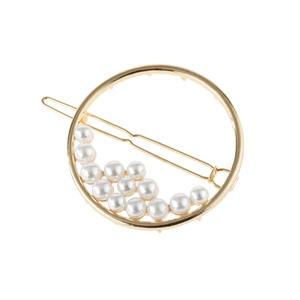 Close-up of circular gold hairpin with white pearls arranged along the inner metal ring