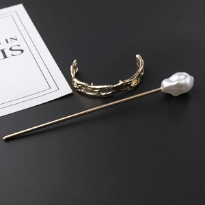 Macro detail of French vintage golden hair pin and textured ring with baroque pearl