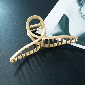 Elegant matte gold zinc alloy large hair claw clip with cross loop handle on magazine background