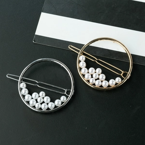 Minimalist circular pearl hair clips in gold and silver finish set on textured background