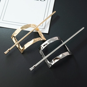 Macro detail of high-polish gold and silver geometric hair pins on grey surface