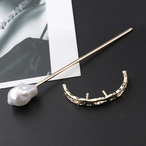 Detail of golden moon-shaped hair clip and baroque pearl hairpin with hammered metal texture