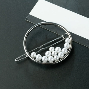 Macro shot of silver alloy circle hair clip with elegant pearls on black texture