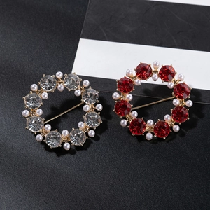 Macro shot of circular brooches with red crystals and pearls on elegant black background