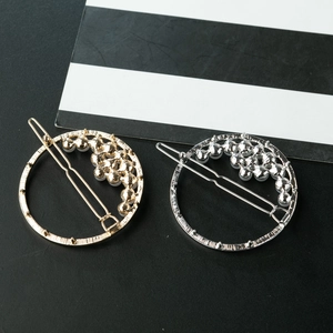 Set of gold and silver hollow circular hair clips with pearls and rhinestones on striped background