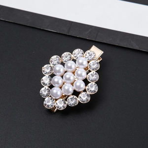 Detail of gold duckbill hair clip featuring white pearls and sparkling rhinestones