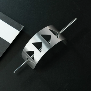 Close-up of brushed silver metal hair stick with geometric hollow triangle design