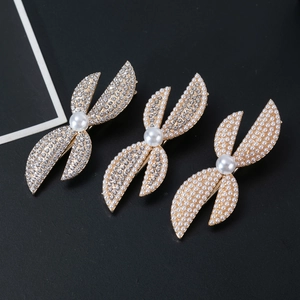 Macro detail of gold hair clips with rhinestones and pearls on a dark textured surface