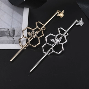 Macro detail of alloy hair pins featuring hollow honeycomb and bee charms in gold and silver