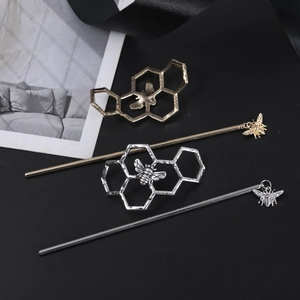 Macro view of golden and silver bee hairpins with hollow honeycomb pattern details