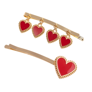 Close-up of golden hairpins with red enamel heart pendants and beaded metal detailing