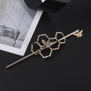 Detailed view of an antique gold hair pin featuring honeycomb patterns and bee pendants