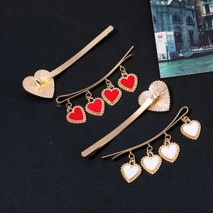 Vintage gold hair clips set with red and white dripping oil heart pendants on black background