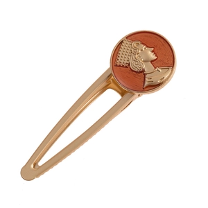 Detail of vintage gold metal hair clip with red enamel embossed royal queen profile