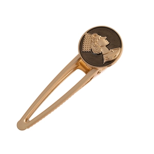Macro detail of a vintage gold alloy hair clip featuring a classic goddess relief emblem