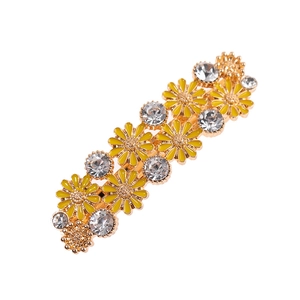 Détail du clip à cheveux avec marguerites jaunes et strass sur une base en métal doré