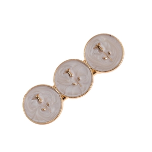 Detailed macro view of retro hair clip featuring beige marble circles and gold rose motifs