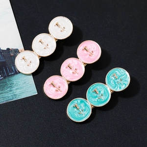 Detail of three rose embossed enamel hair clips with marble texture on a black background