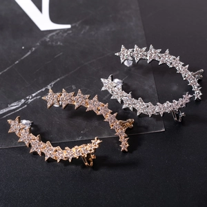 Close-up of sparkling star-shaped ear crawlers in gold and silver with rhinestones