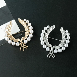 Détail des broches épis de blé dorées et argentées avec d'élégantes perles blanches