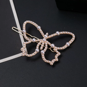 Gros plan sur la barrette papillon dorée ornée de perles blanches élégantes et raffinées