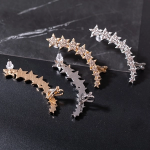Detailed view of silver and gold plated star crawler earrings with crystal pavé on black marble